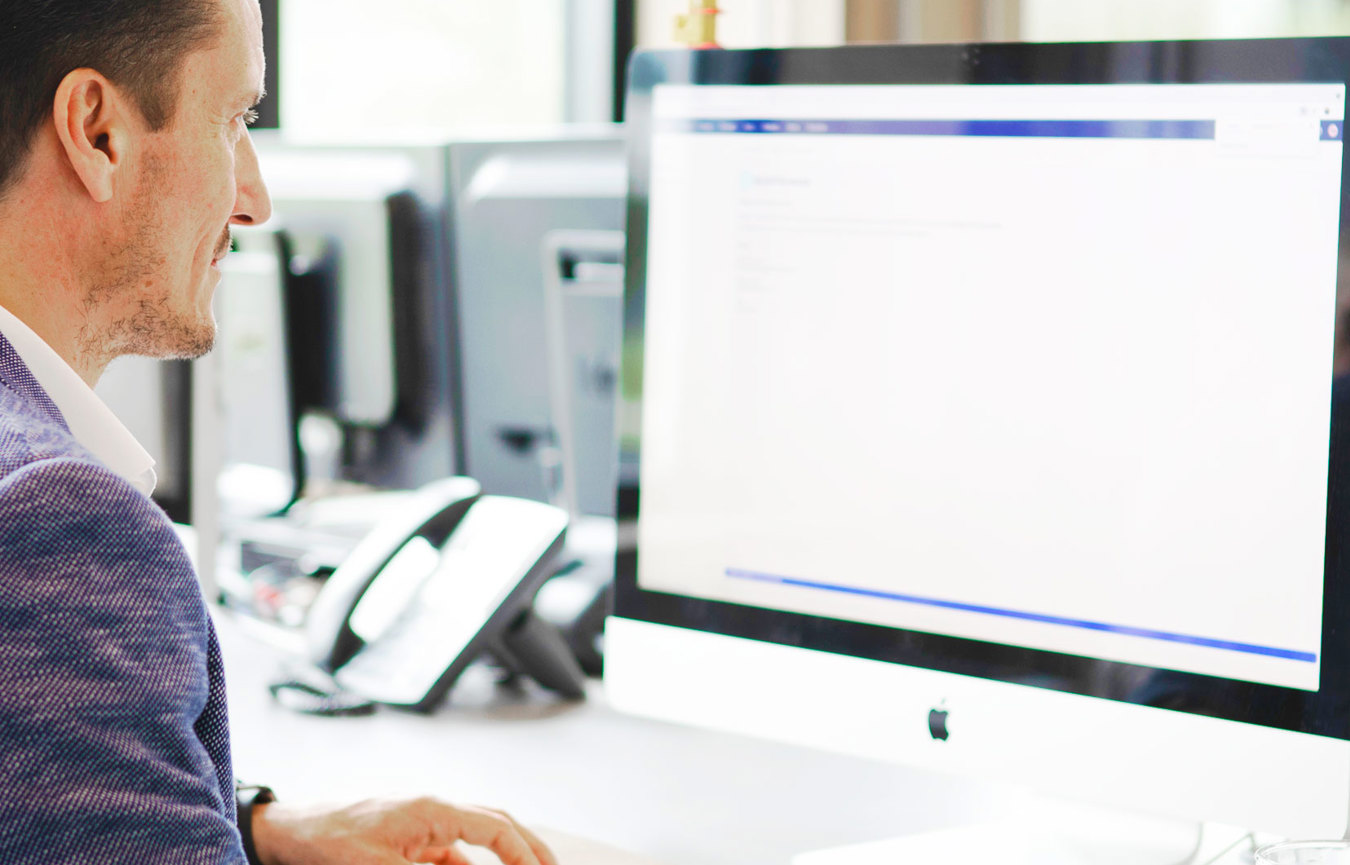 Een man die aan een bureau zit en een computer gebruikt